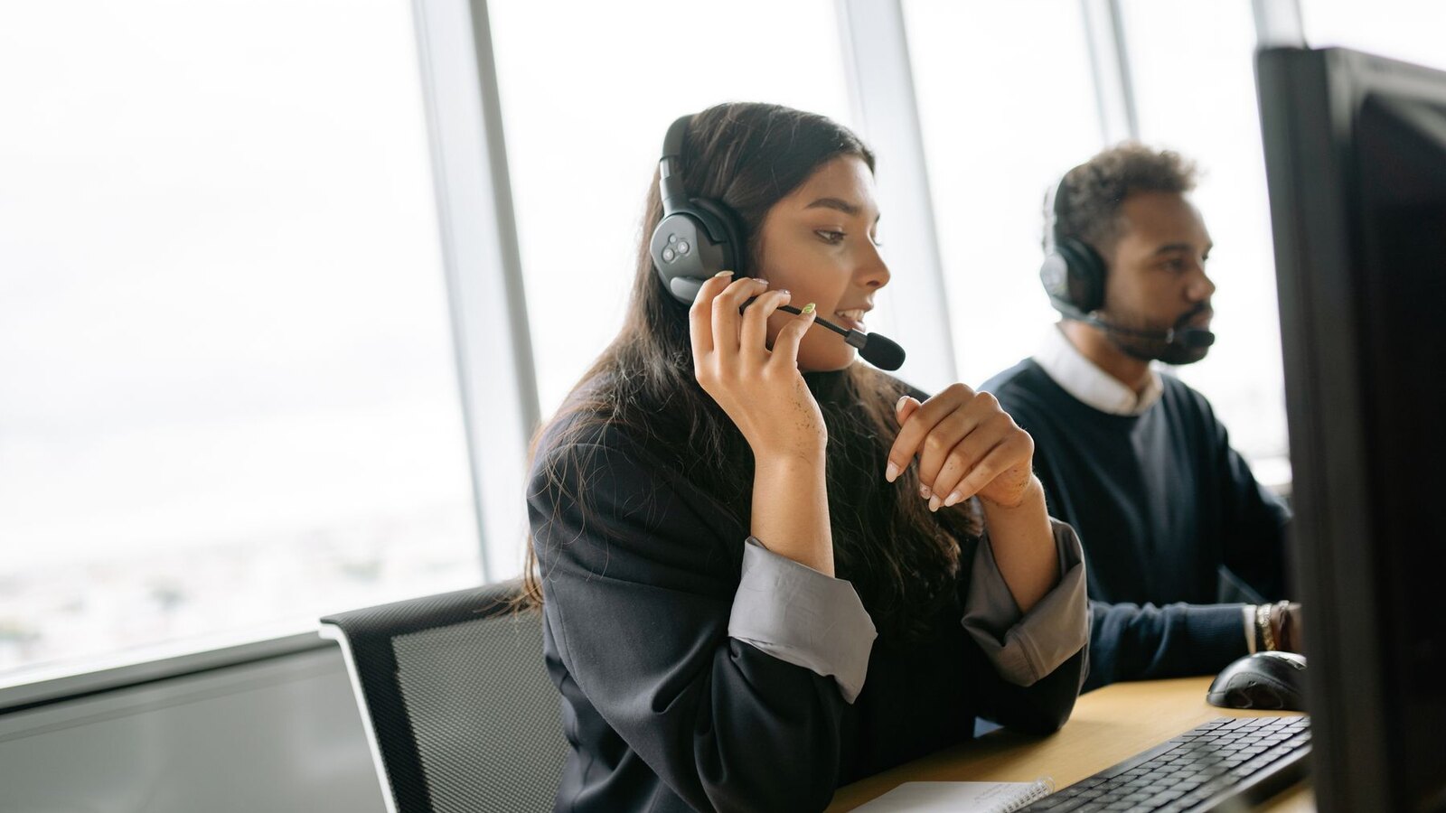 Petugas layanan pelanggan memakai headset saat bekerja di kantor